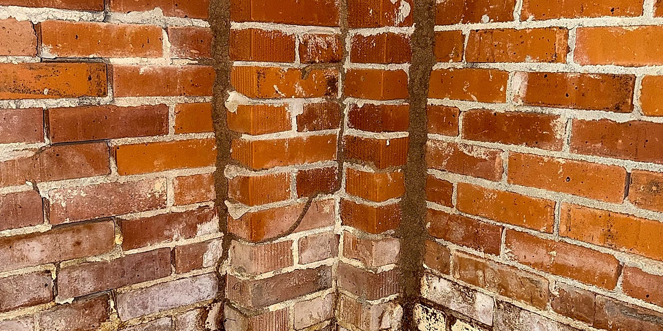 Termite mud tubes climbing the brick foundation corner of a Pine Belt home