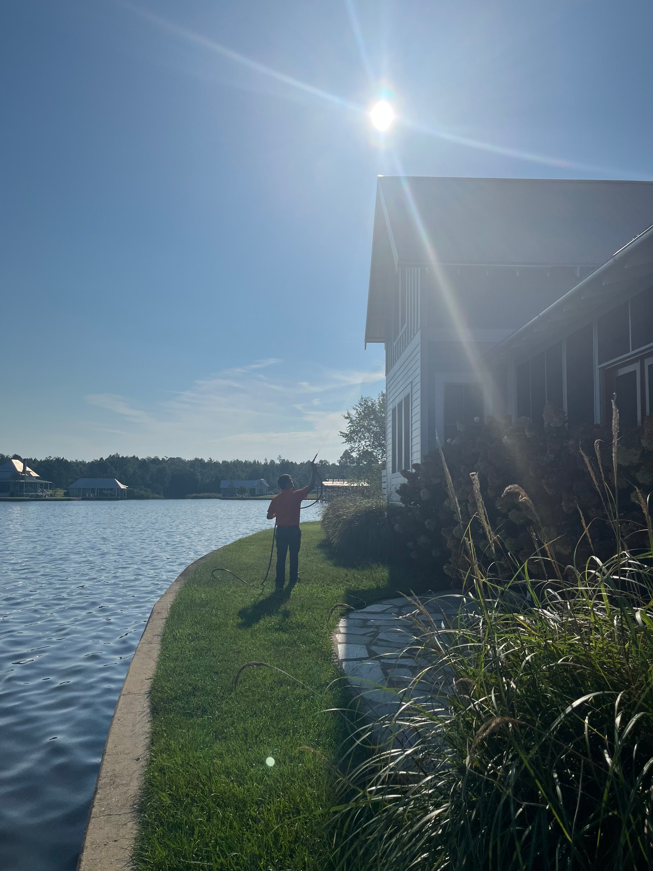 A Parker's Pest Management technician treating the outside of a lakeside home in the Pine Belt