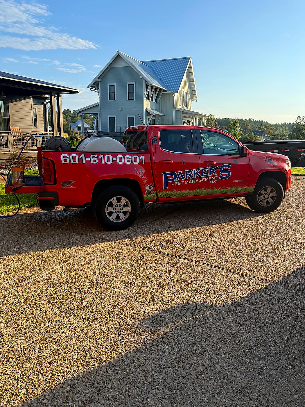 A Parker's Pest Management truck at a home, the phone number along the bed